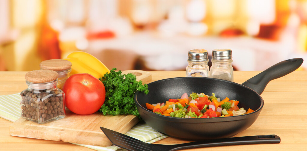 Vegetable ragout in pan,  on wooden table on bright background