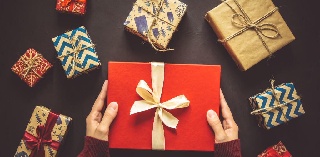 Woomen's hands holding gift box. Present boxes background. Top view. Flat lay. Toned image