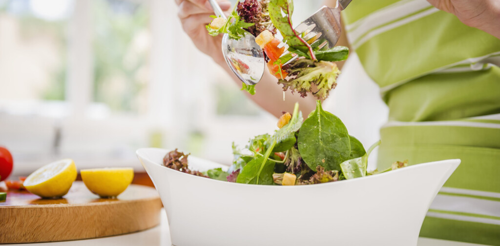Hispanic woman tossing salad in domestic kitchen