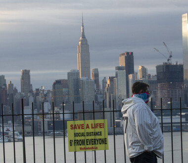 WEEHAWKEN, NJ - APRIL 06: A man covers his face as the sun rises behind in Manhattan on April 6, 2020 as seen from Weehawken, New Jersey. The U.S. COVID-19 death toll has now surpassed 9,000. (Photo by Kena Betancur/Getty Images)