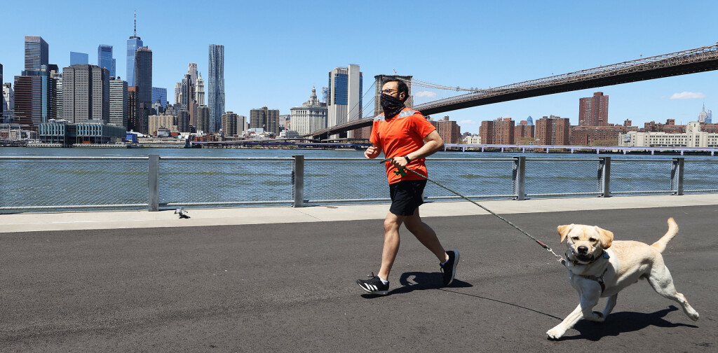 BROOKLYN, NEW YORK - APRIL 28: A Man runs with his dog while wearing a mask amidst the coronavirus pandemic at Brooklyn Bridge Park on April 28, 2020 in the Brooklyn Borough of New York City. The World Health Organization declared coronavirus (COVID-19) a global pandemic on March 11th. (Photo by Al Bello/Getty Images)