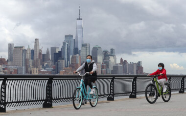 HOBOKEN, NJ - MAY 1: People wear masks as they ride their bicycles in front of the skyline of lower Manhattan and One World Trade Center in New York City on May 1, 2020 in Hoboken, New Jersey. (Photo by Gary Hershorn/Getty Images)