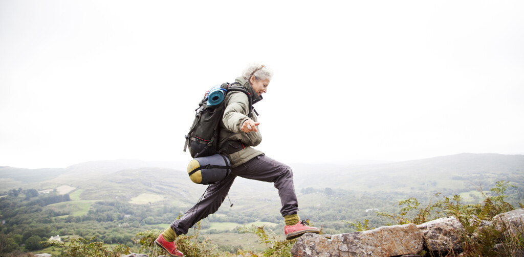 Older woman happily trekking in the mountains of ireland, solo travelor enjoying freedom and independence.