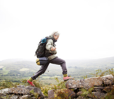 Older woman happily trekking in the mountains of ireland, solo travelor enjoying freedom and independence.