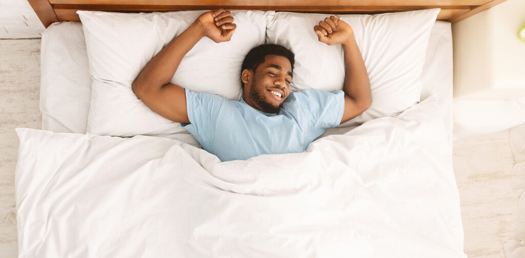 Sweet dreams. Peaceful black guy enjoying nap, resting in bed, top view with empty space